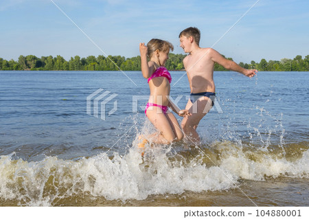 Children play in the water jumping on the waves. Children's vacation Children play in the water jumping on the waves. Children's vacation 104880001