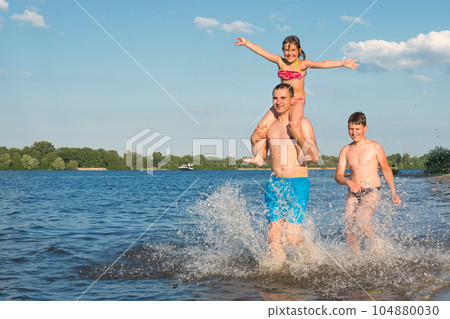 Family beach games in the water. Family runs along the beach on a sunny day, vacation Family beach games in the water. Family runs along the beach on a sunny day, vacation 104880030