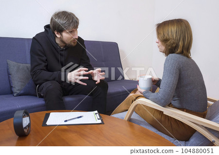 Young woman talking to a psychologist in an office. The concept of a psychological consultant Young woman talking to a psychologist in an office. The concept of a psychological consultant 104880051