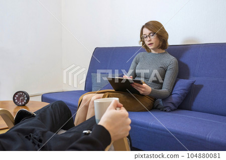 A young psychologist writes notes while communicating with a patient. A young psychologist writes notes while communicating with a patient. 104880081