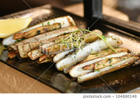 The shells knives, parsley and half a lemon on black plate The shells knives, parsley and half a lemon on black plate 104880148