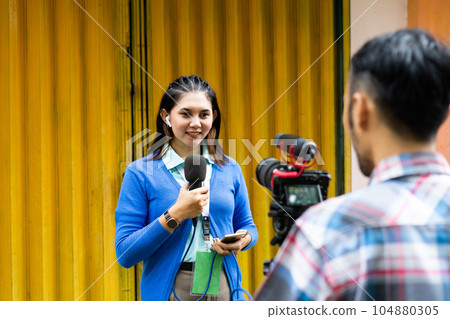 a beautiful reporter and the cameramen recording videos for news material 104880305