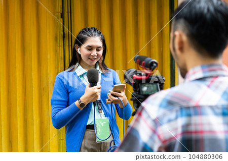 a reporter look at her phone while recording videos for news material 104880306