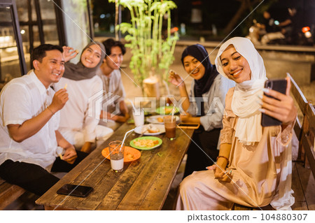 woman in hijab holds making video call during iftar with friends 104880307