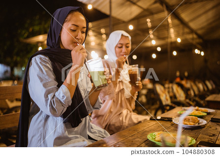 veiled Muslim woman drinks before eating while breaking fast veiled Muslim woman drinks before eating while breaking fast 104880308