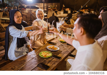 Women in hijab and friends toast together before drinking during iftar Women in hijab and friends toast together before drinking during iftar 104880316