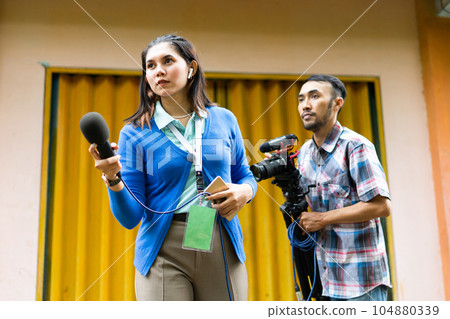 a female reporter hunting for news with a cameraman behind her a female reporter hunting for news with a cameraman behind her 104880339