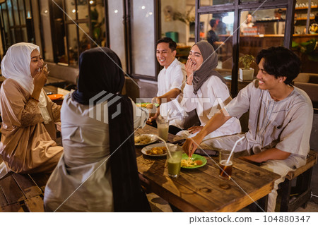Muslim woman wearing hijab and Muslim man joking while breaking fast Muslim woman wearing hijab and Muslim man joking while breaking fast 104880347