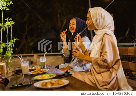 Asian young woman in hijab meal while breaking fast at outdoor cafe Asian young woman in hijab meal while breaking fast at outdoor cafe 104880362