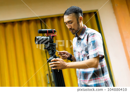 a handsome cameraman preparing his shooting equipment 104880410