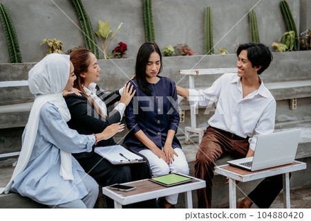 young woman is sad and comforted by friends while sitting together young woman is sad and comforted by friends while sitting together 104880420