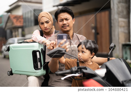 family riding motorbike scooter together using mobile phone family riding motorbike scooter together using mobile phone 104880421