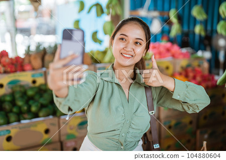 female customer standing with thumb up while taking selfie photo female customer standing with thumb up while taking selfie photo 104880604
