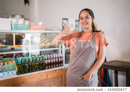 attractive female stall owner wearing apron showing thumbs up 104880657