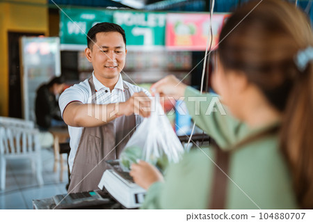 male seller putting the plastic bag on the scale 104880707