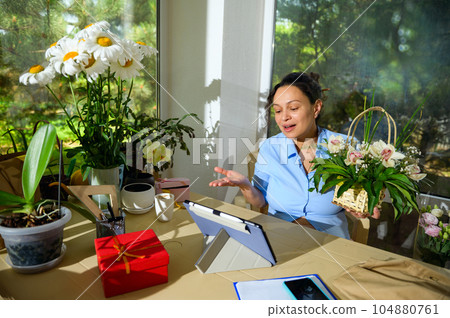 Inspired happy pregnant woman talking via video link using digital tablet, discussing orders for floral arrangements Inspired happy pregnant woman talking via video link using digital tablet, discussing orders for floral arrangements 104880761