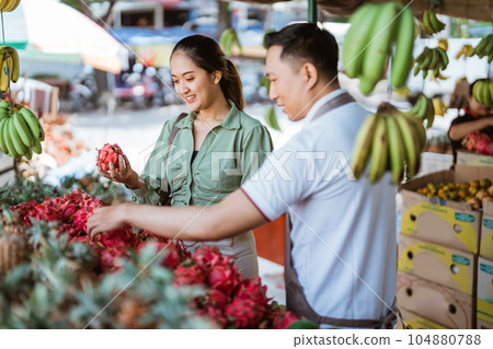 male employee helping the customer choosing the dragon fruits 104880788