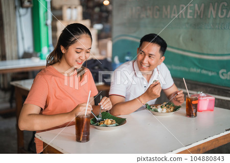 Attractive girl and handsome man eating together in food stall 104880843
