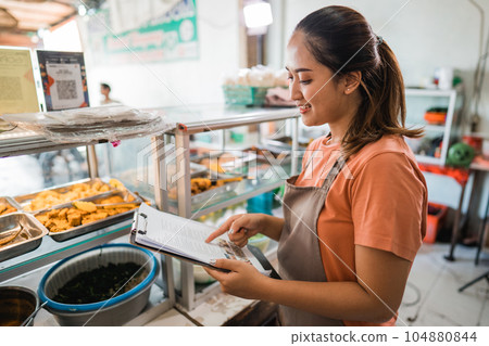 female stall owner in apron checking material shopping on clipboard female stall owner in apron checking material shopping on clipboard 104880844