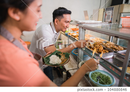 male buyer points to the food he wants helped assistant 104880846