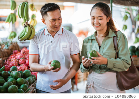 couple of customer smiling while choosing the avocados 104880866