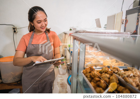 waitress checking preparations at a traditional food stall display waitress checking preparations at a traditional food stall display 104880872