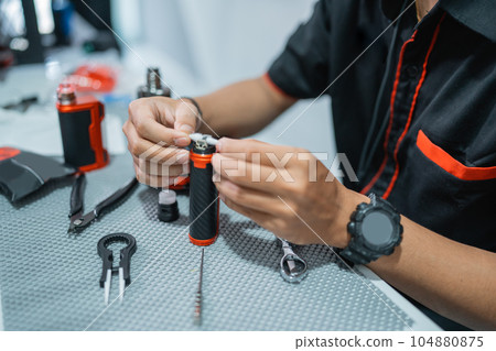 the hands of male vape seller changing the vape cotton the hands of male vape seller changing the vape cotton 104880875