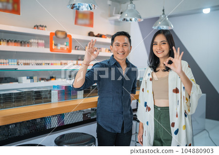couple of vape seller standing back to back with oke hand gesture couple of vape seller standing back to back with oke hand gesture 104880903