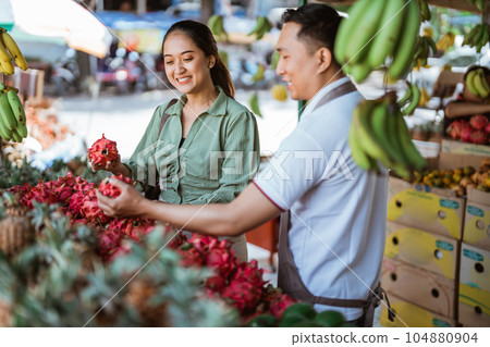 female customer helped by the male employee to choosing the dragon fruits 104880904