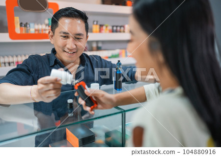 male shopkeeper helping the female customer to refill the liquid male shopkeeper helping the female customer to refill the liquid 104880916