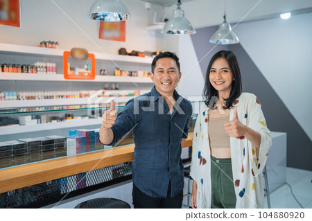 couple of vape seller standing back to back with handcrossed couple of vape seller standing back to back with handcrossed 104880920