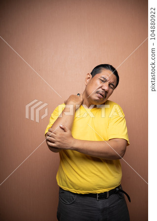 old asian man suffering from shoulder pain with clenching his shoulder old asian man suffering from shoulder pain with clenching his shoulder 104880922
