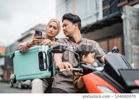 family riding motorbike scooter together using mobile phone 104880970