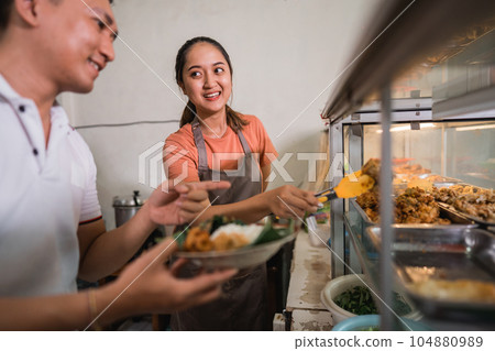 female waitress serving Asian man customer at a traditional stall 104880989