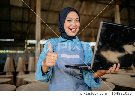 joyful veiled asian woman using computer laptop with showing thumbs up 104881036