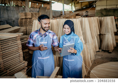 Male and female entrepreneurs in hijab use tablets together 104881038