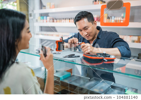 male vape shopkeeper changing the cotton coil while the female customer vaping 104881140