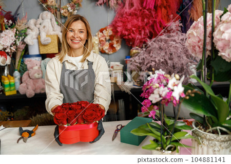 Smiling woman florist flower shop owner hold roses composition ready to sell on store background Smiling woman florist flower shop owner hold roses composition ready to sell on store background 104881141