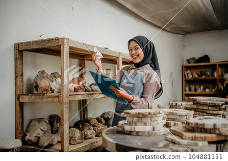 smiling veiled woman holding a stone craft and clipboard smiling veiled woman holding a stone craft and clipboard 104881151