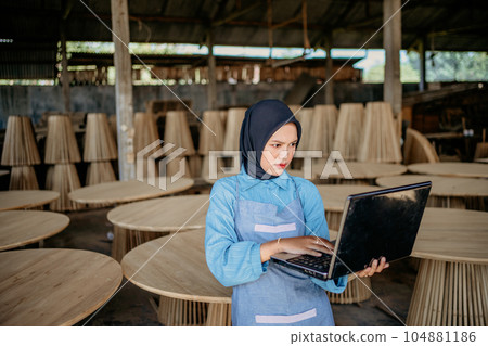 Veiled woman is using laptop computer at furniture craft shop Veiled woman is using laptop computer at furniture craft shop 104881186