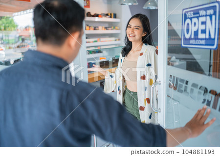 beautiful female shopkeeper smiling while welcoming the male customer beautiful female shopkeeper smiling while welcoming the male customer 104881193