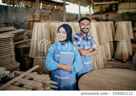 two smiling Asian entrepreneurs wearing aprons stand together with crossed hands two smiling Asian entrepreneurs wearing aprons stand together with crossed hands 104881212