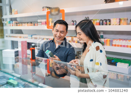 couple of shopkeeper using the digital tablet while observing the vape mode couple of shopkeeper using the digital tablet while observing the vape mode 104881240