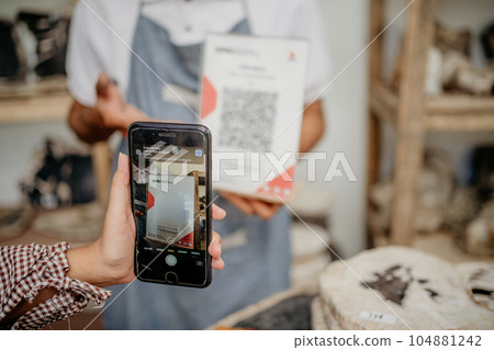 Person using a smartphone scanning something for cashless payment Person using a smartphone scanning something for cashless payment 104881242