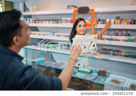 beautiful shopkeeper taking the liquid at the shelf beautiful shopkeeper taking the liquid at the shelf 104881259