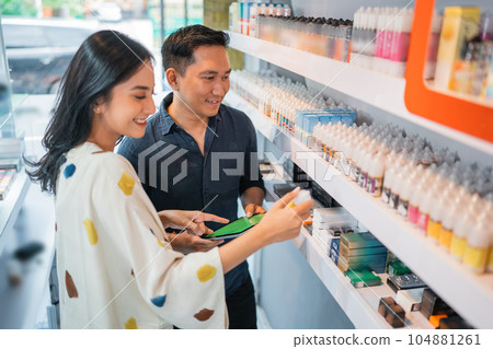 couple of shopkeeper using the digital tablet while observing the liquid stock couple of shopkeeper using the digital tablet while observing the liquid stock 104881261