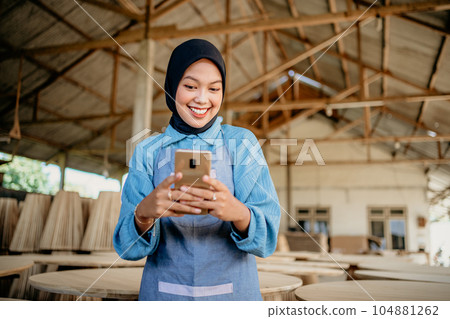 Muslim female entrepreneur uses a smartphone to send messages Muslim female entrepreneur uses a smartphone to send messages 104881262