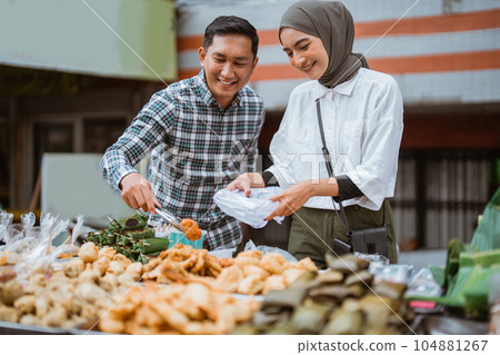 muslim couple are shopping in a food stall or street vendor muslim couple are shopping in a food stall or street vendor 104881267