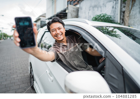 male driver showing his mobile phone screen while sitting in a car male driver showing his mobile phone screen while sitting in a car 104881285