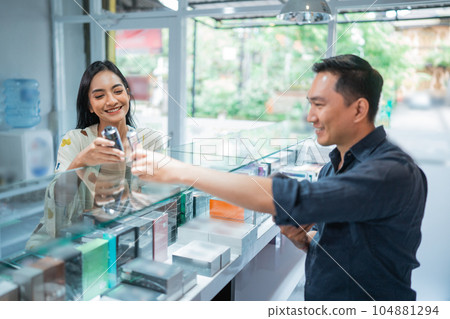 female customer checking the vape mod helped by the male shopkeeper 104881294